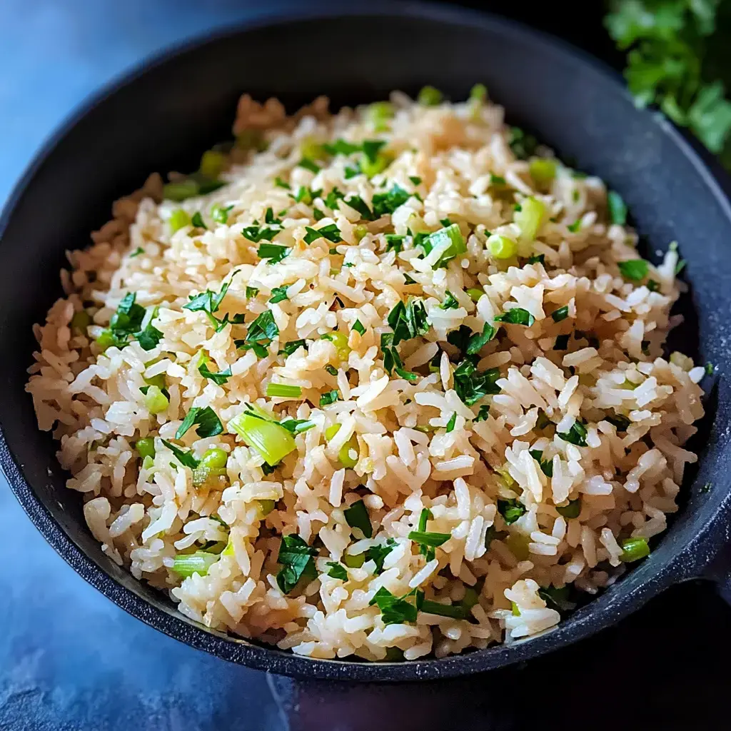 A close-up of a bowl of rice garnished with chopped green herbs.