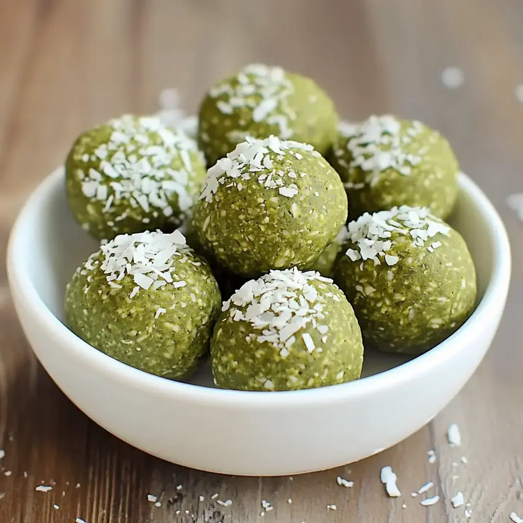 A bowl filled with green energy balls topped with shredded coconut.