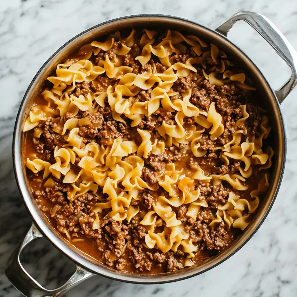 A pot filled with cooked egg noodles and ground beef in a savory sauce.