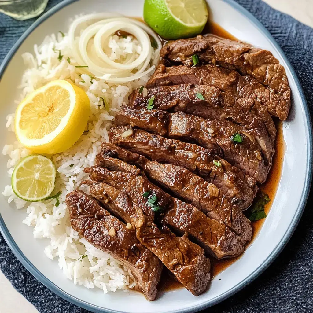 A plate of sliced beef served with white rice, garnished with lemon and lime wedges, and onion slices.