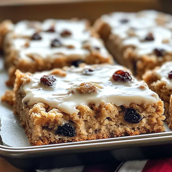 A tray of cake with white frosting and raisins.