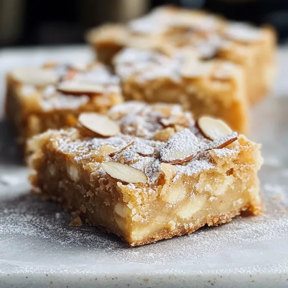 A square piece of cake with almonds on top.
