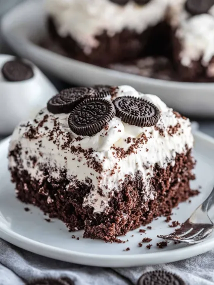 A slice of chocolate cake with white frosting and chocolate chips.