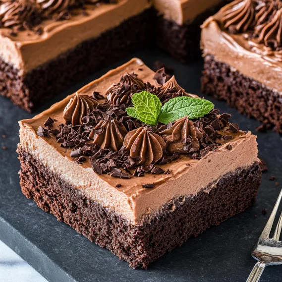 A slice of chocolate cake with a green leaf on top.