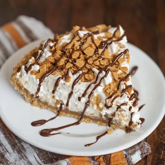 A slice of pie with chocolate drizzled on top.