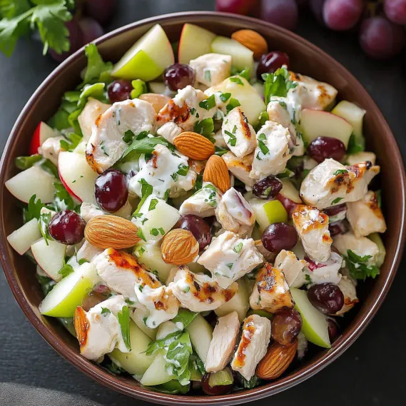 A bowl of food with chicken, apples, and cherries.