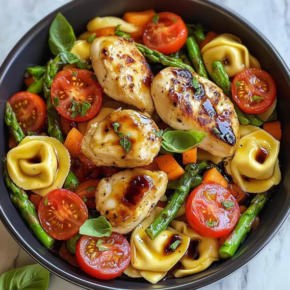 A bowl of food with chicken, tomatoes, and pasta.