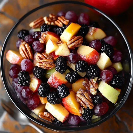 A bowl of fruit with blackberries, apples, and peaches.