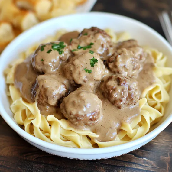 A bowl of pasta with meatballs and gravy.