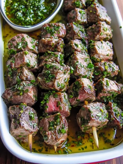 A plate of meat skewers with a bowl of sauce.