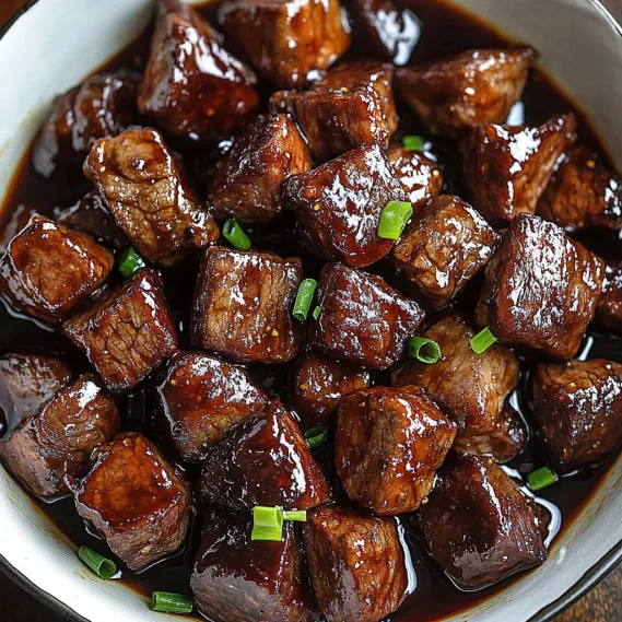 A bowl of beef with gravy.
