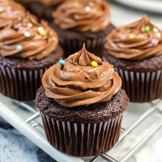 A chocolate cupcake with chocolate frosting and sprinkles.