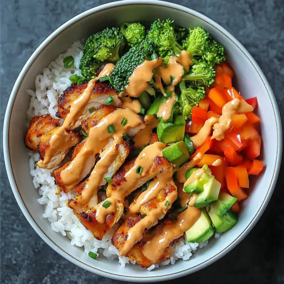 A bowl of food with rice, broccoli, carrots, and chicken.