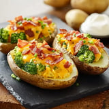 Baked potatoes topped with broccoli, cheese, and bacon bits, served on a slate platter.