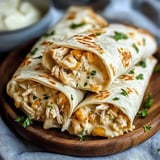 Three stuffed tortillas filled with shredded chicken, cheese, and corn, garnished with parsley, are displayed on a wooden plate.